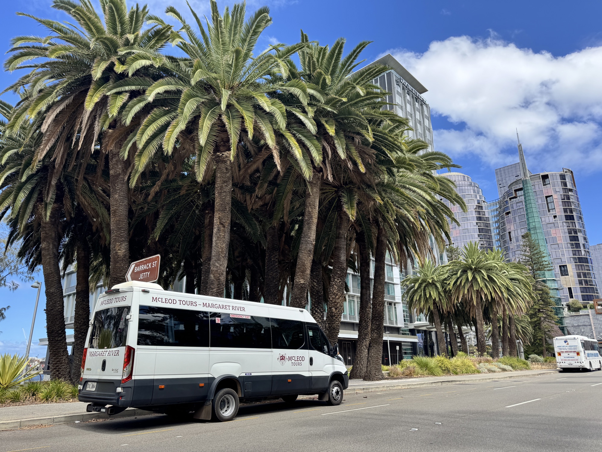 The white McLeod Tours Iveco Daily waiting under the palms at Barrack Street Jetty in Perth