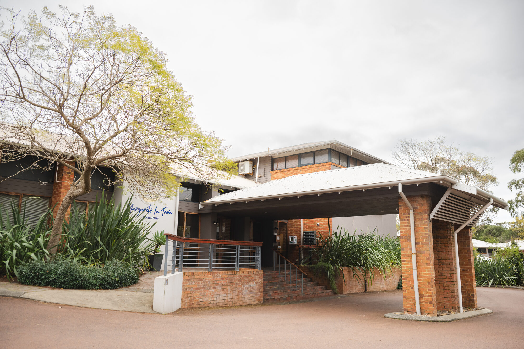 The front of Margaret's In Town, signage above the door and a jacaranda over the drive