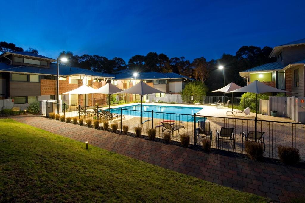 The pool lit at dusk, umbrellas out and the apartments glowing behind it