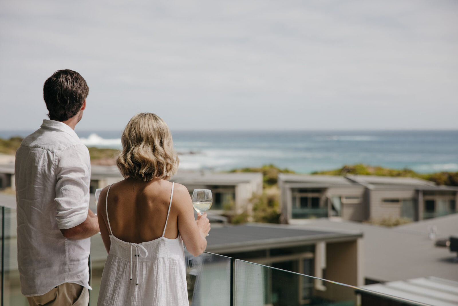 Guests at a balcony rail looking out over the villas to the ocean