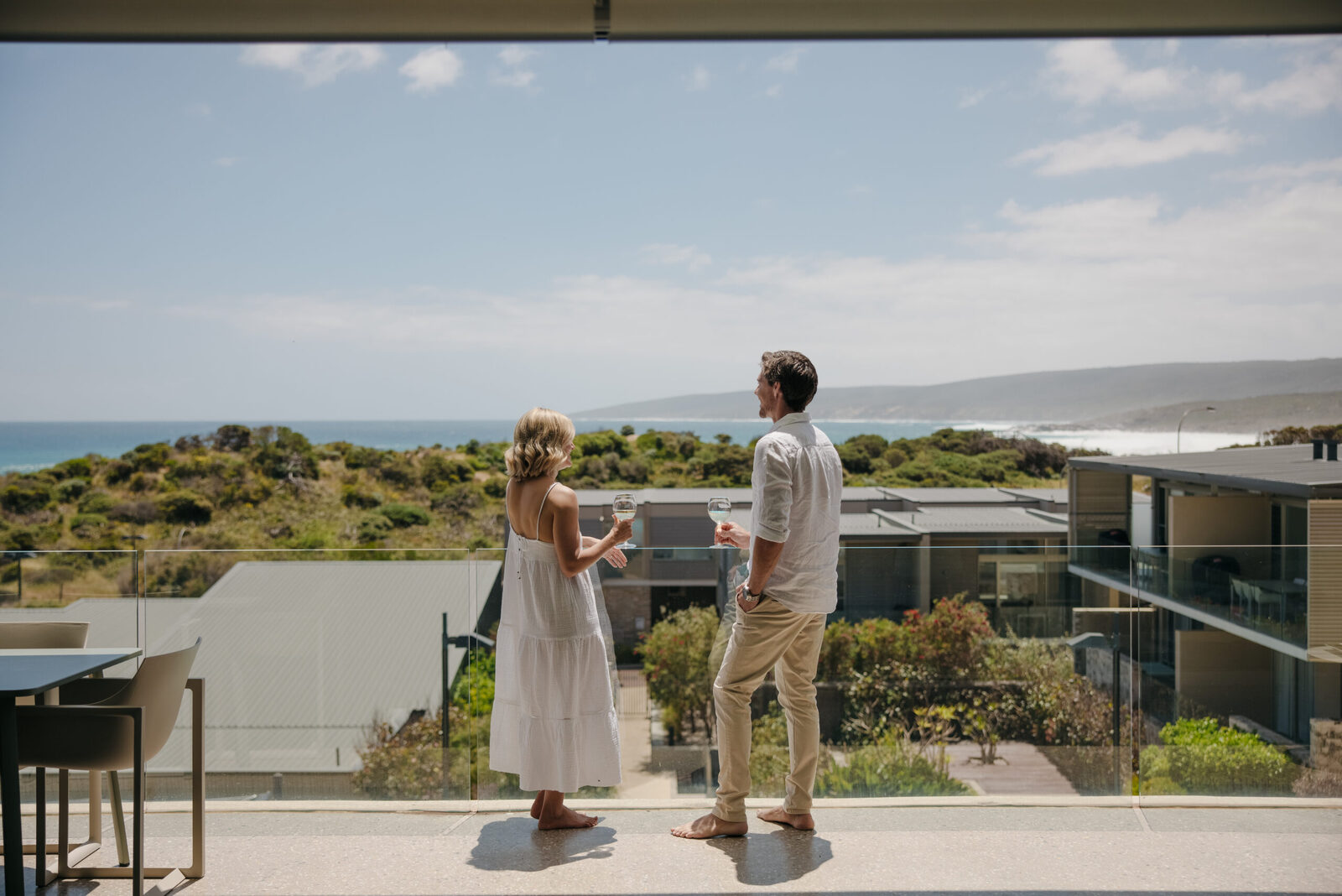A couple with drinks on the terrace above the dunes
