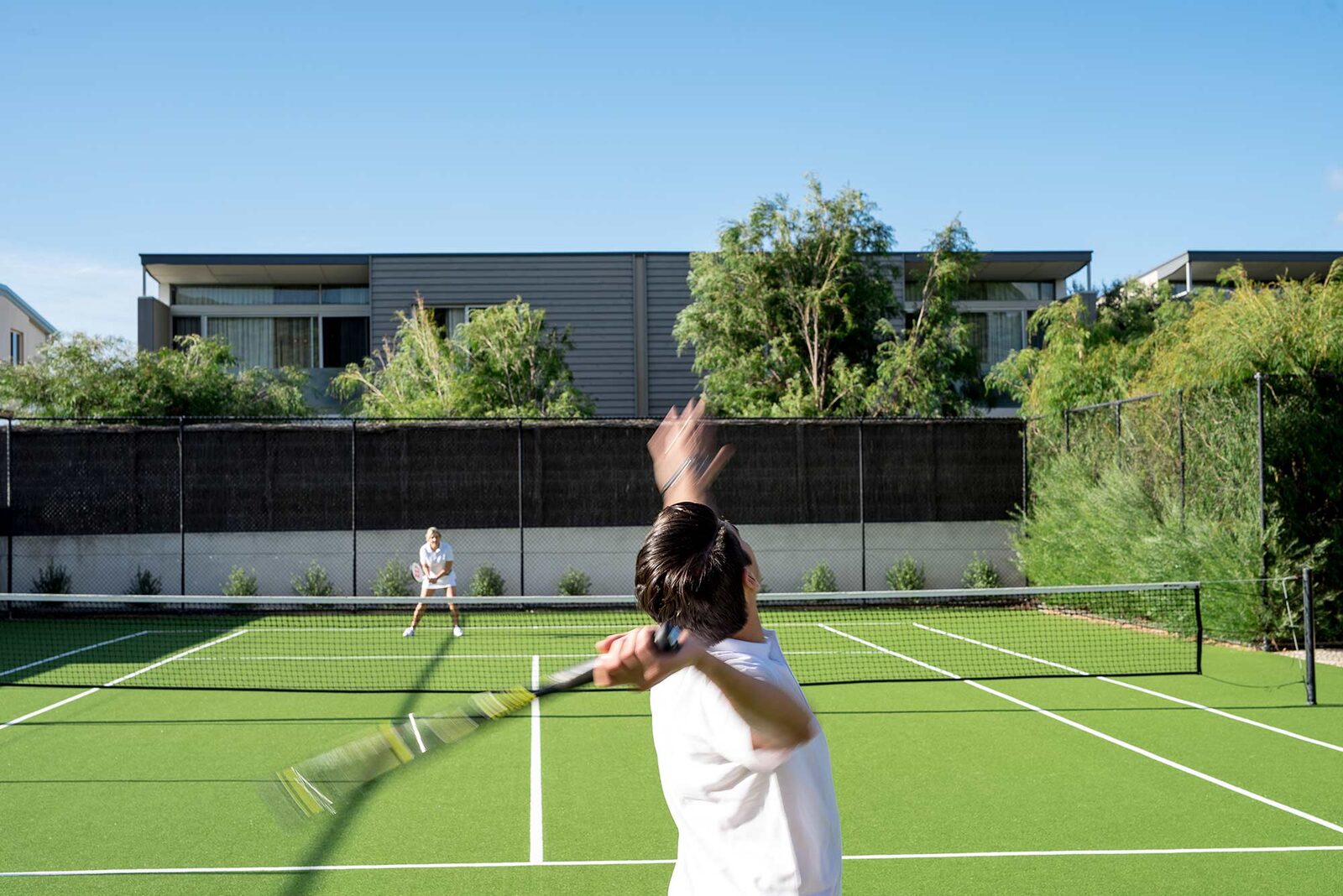 The full-size tennis court in play, villas along the far side