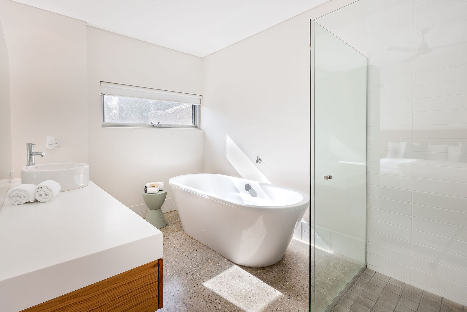 The ensuite: a freestanding bath under a high window, glass shower alongside