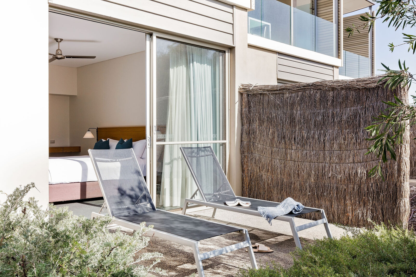 The private courtyard, two sun loungers behind a reed screen, the bedroom opening onto it