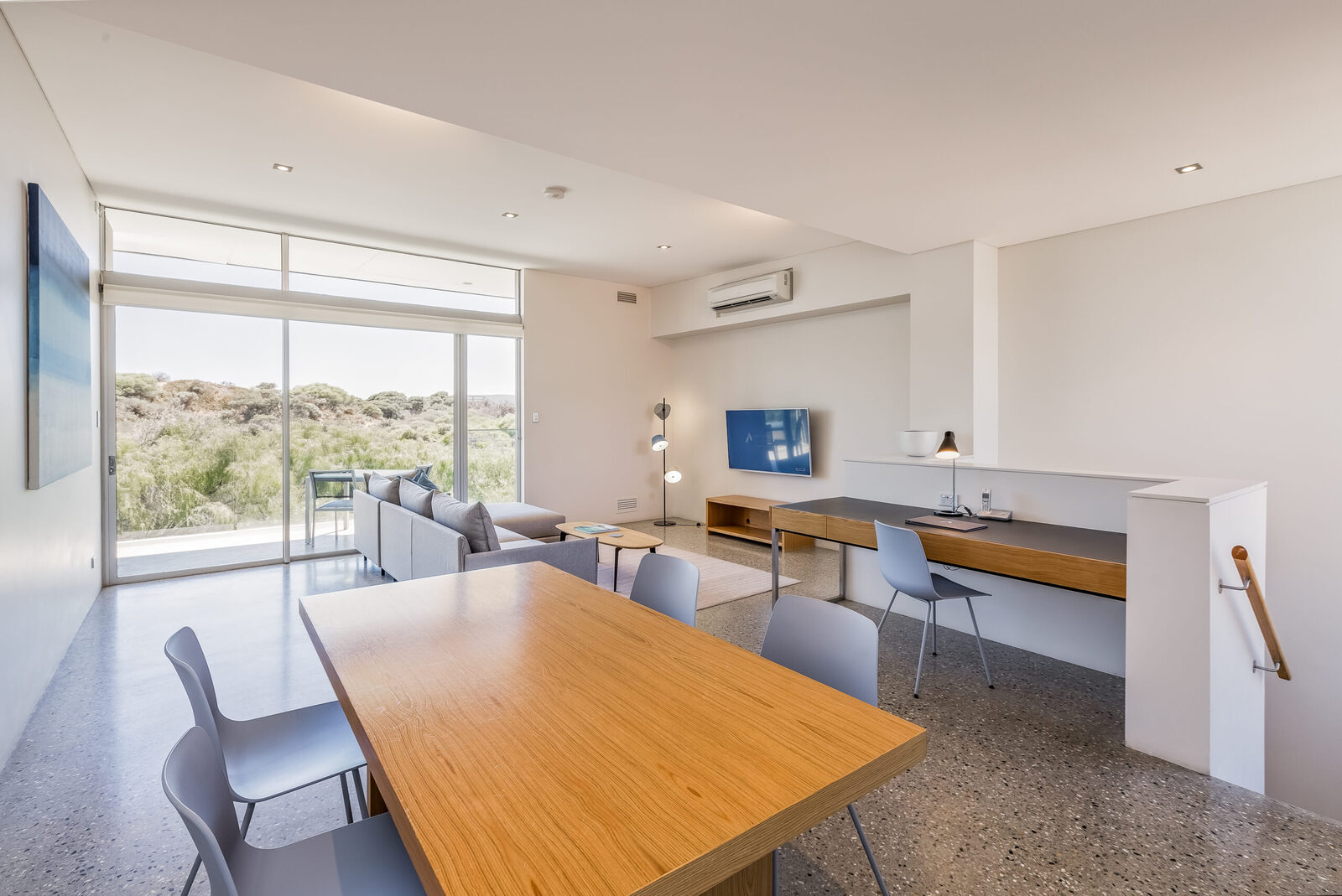 The dining table seating six, with a desk and television along the wall behind