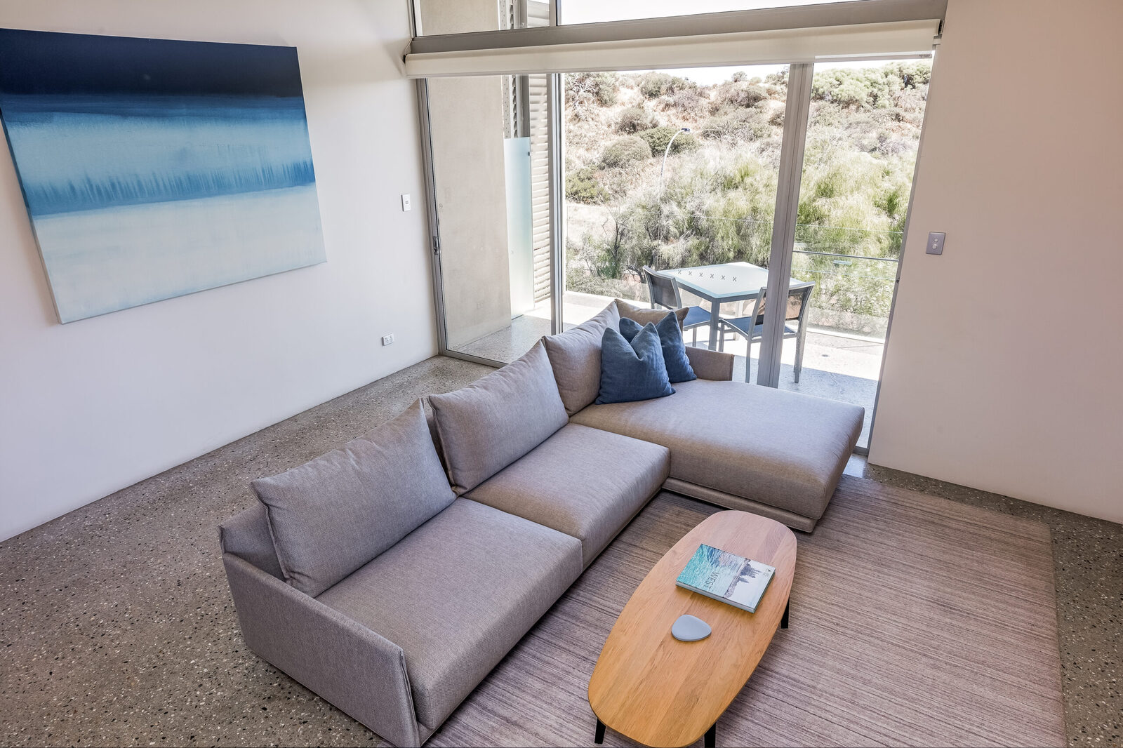 The living area from the stairs, a blue horizon painting above the corner sofa