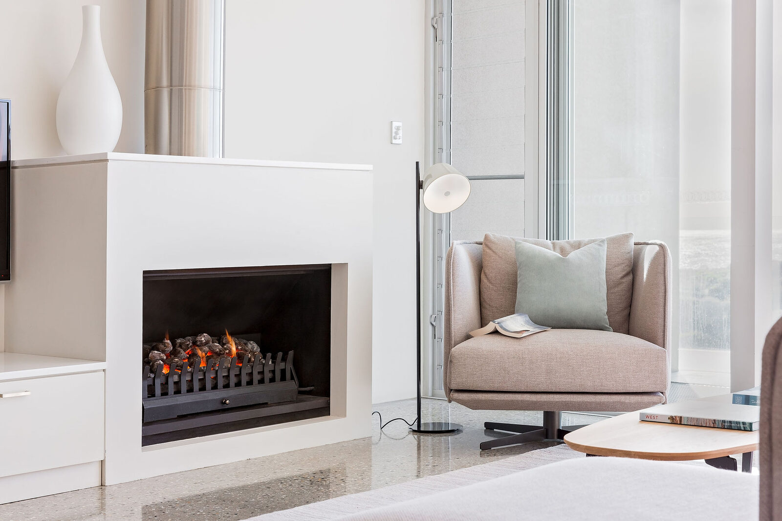 The Jetmaster fireplace alight, a swivel armchair drawn up beside it