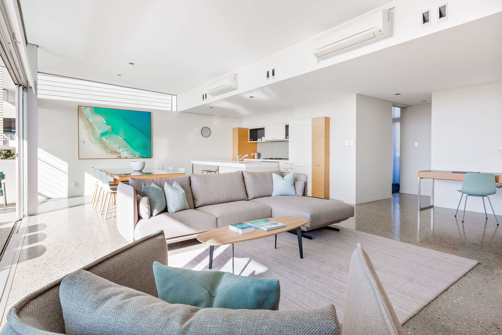 Looking back across the sofa to the dining table, kitchen and desk