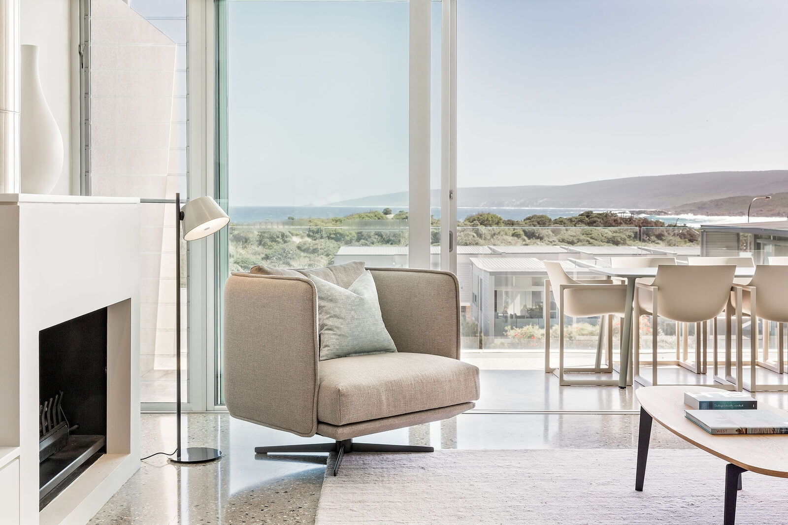 The lounge with the ocean filling the window, balcony table beyond the glass