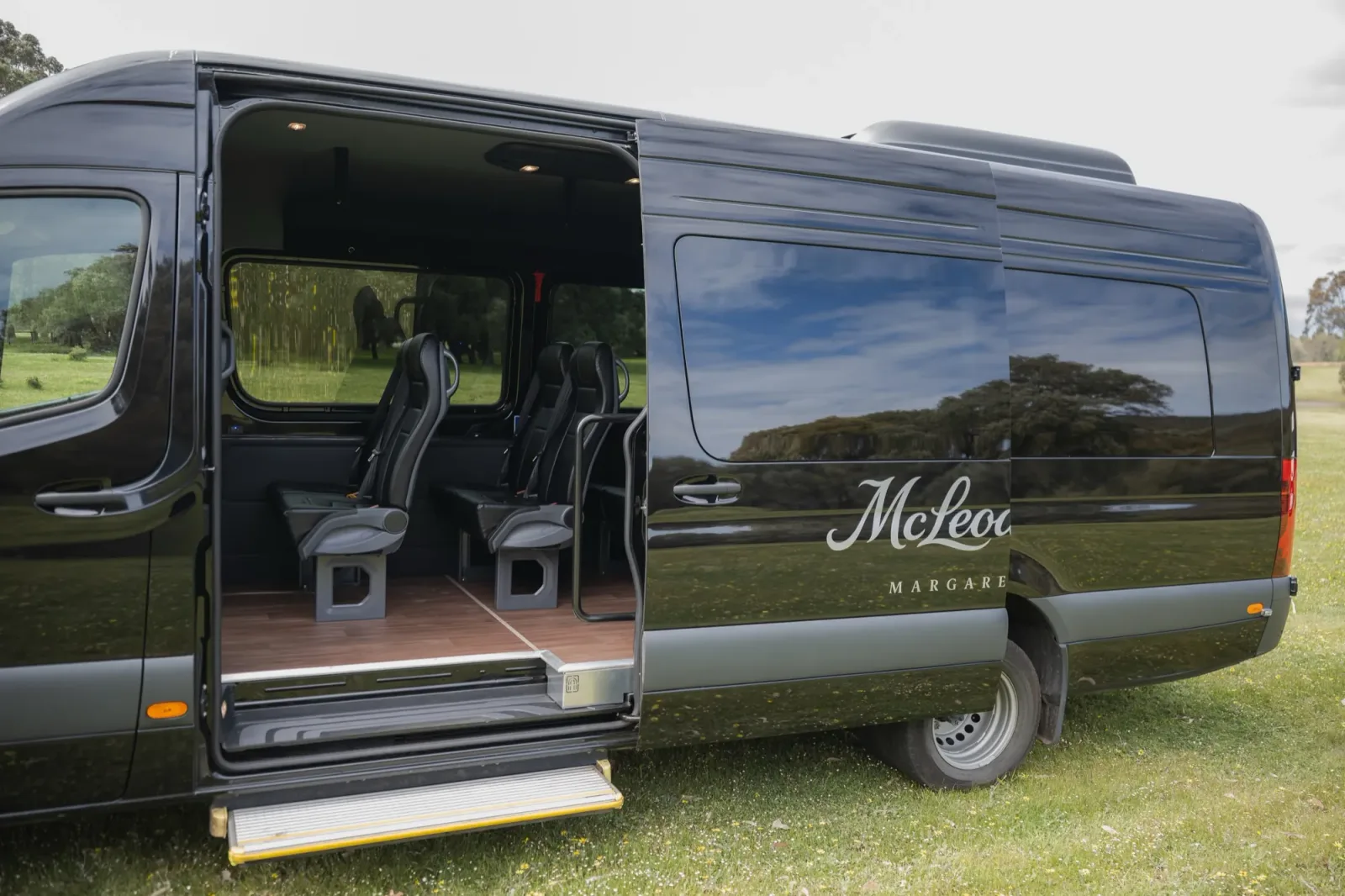McLeod Tours Mercedes-Benz Sprinter passenger side door open, automatic step & view into the rear with black leather reclining seats