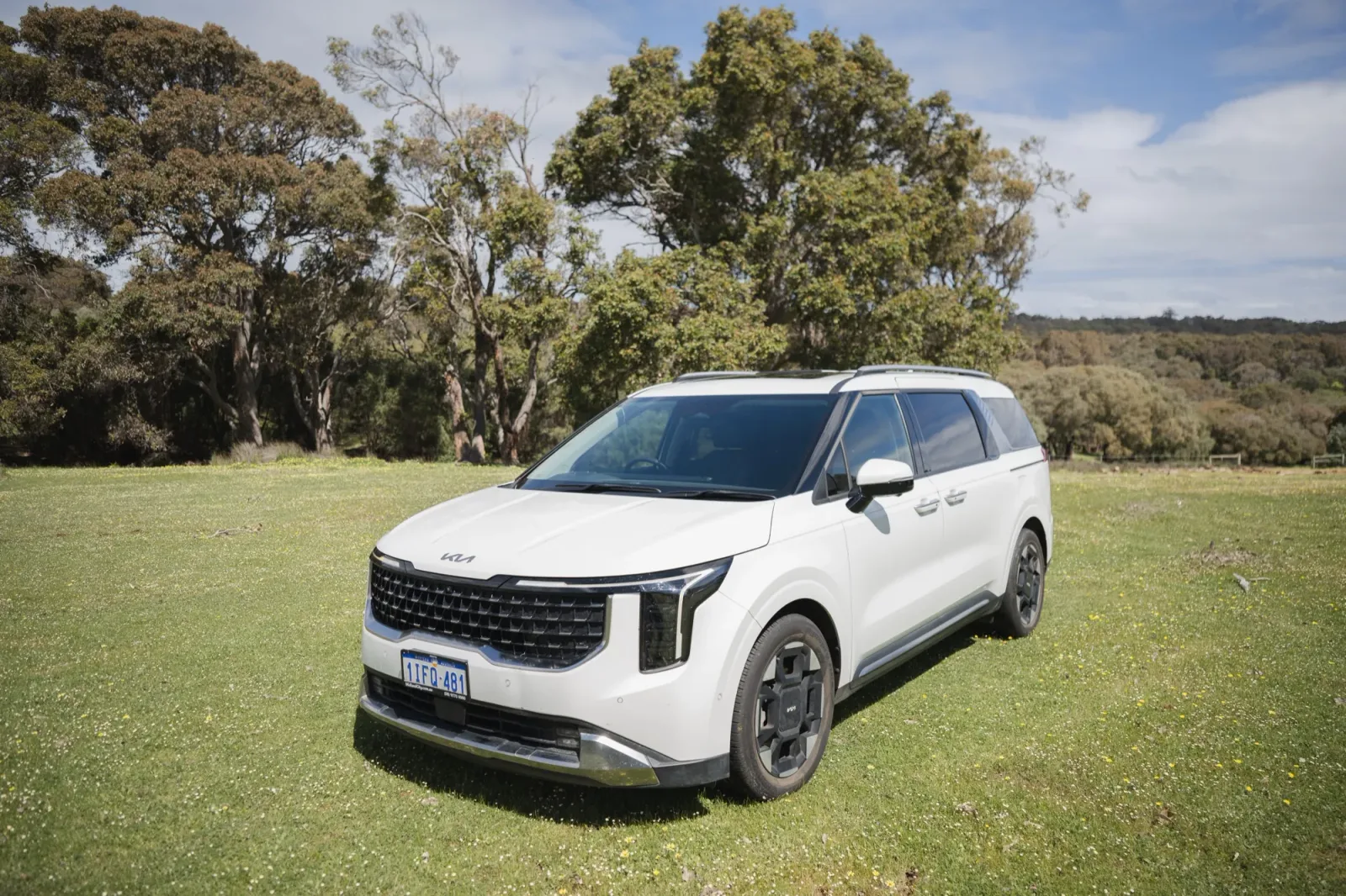 The white McLeod Tours Kia Carnival from passenger side