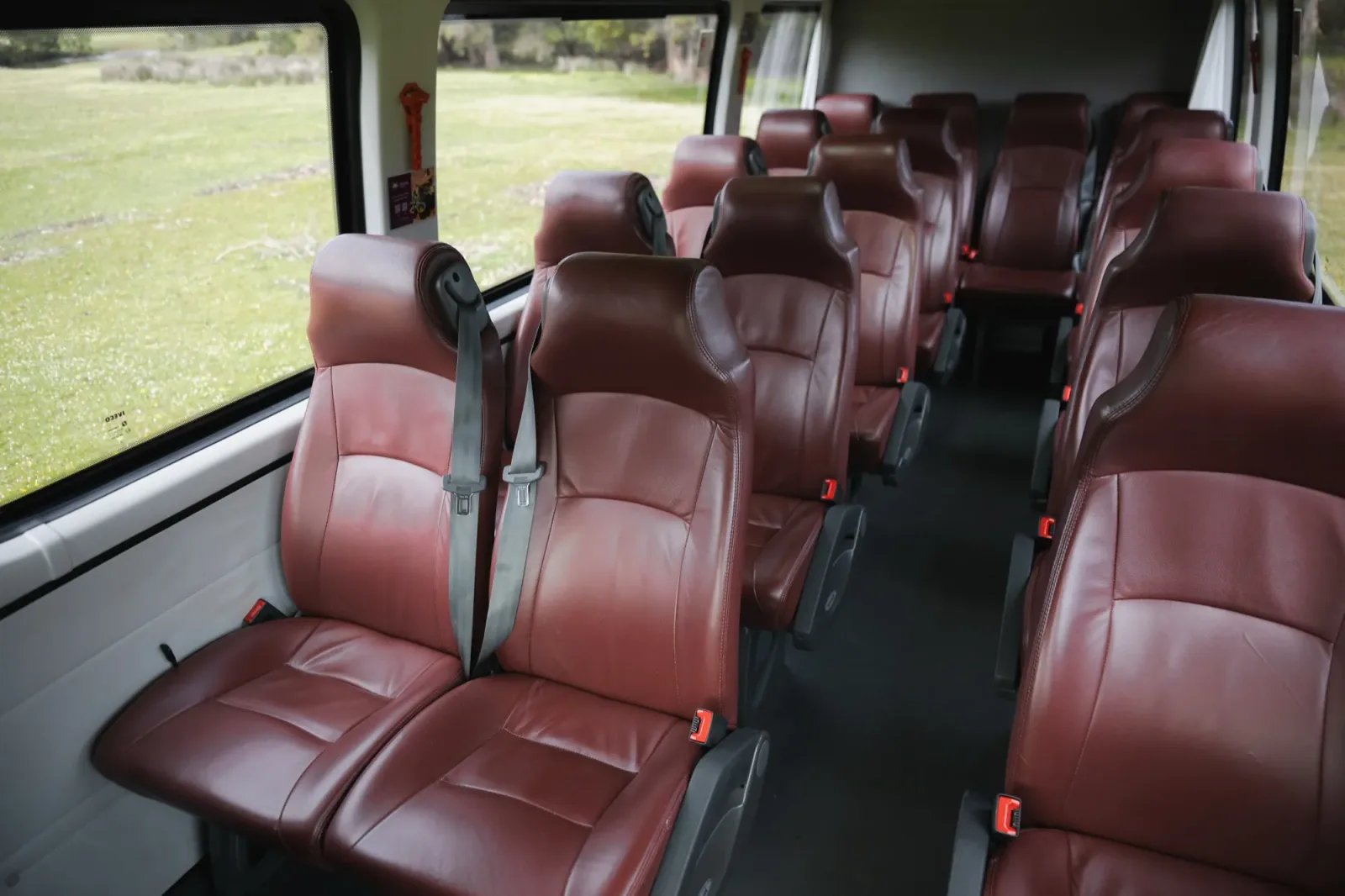Looking down the centre aisle of the Iveco Daily, burgundy leather seats in rows either side